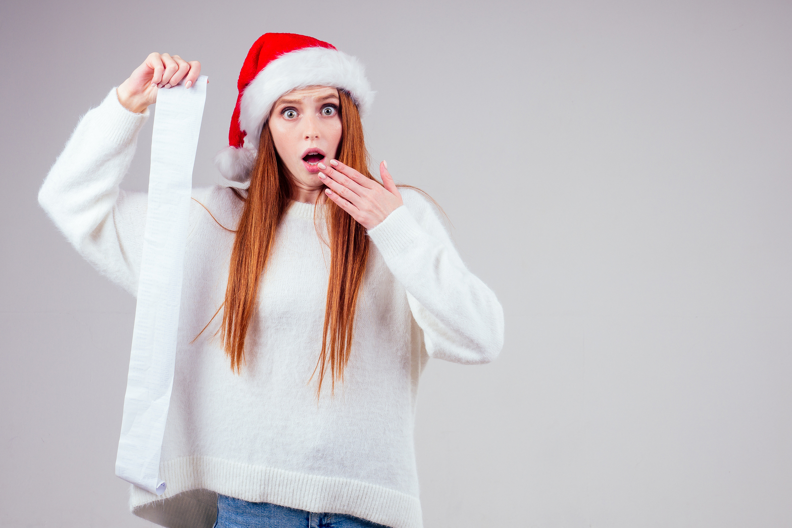 person in Santa Hat holding a long gift list