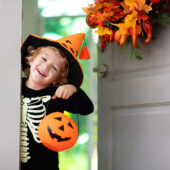 Little girl in halloween costume trick or treat at door